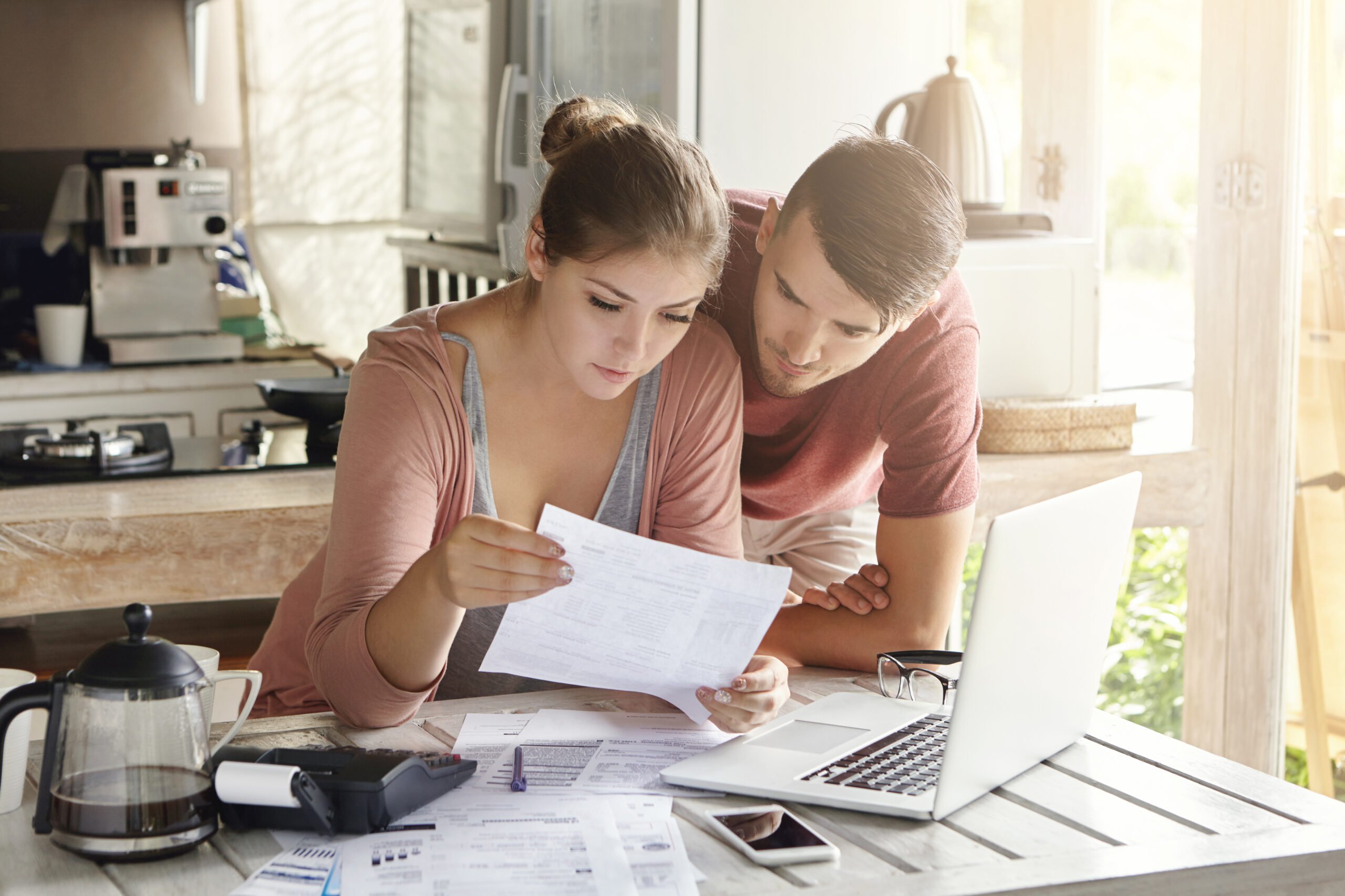 Young couple looking at paperwork and laptop